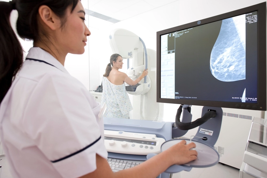 Female Technologist Viewing Breast Image During A Mammogram