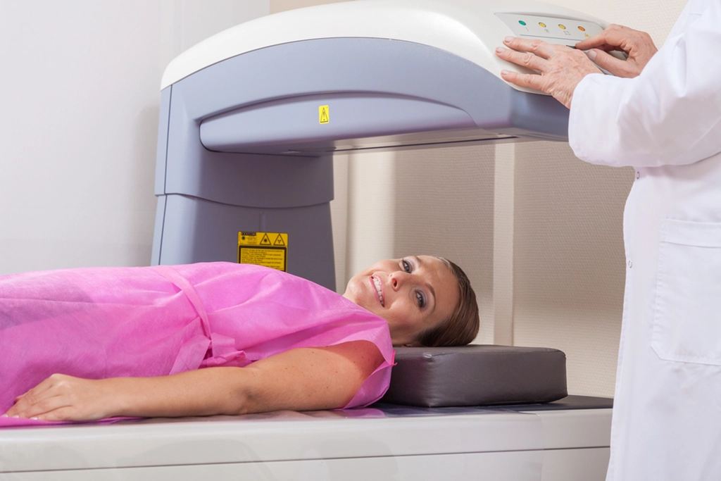 Female Patient Undergoing A DEXA Scan With Female Technologist
