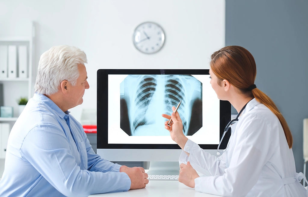 Referring Doctor Discussing Chest X-Ray Results With Patient In Exam Room